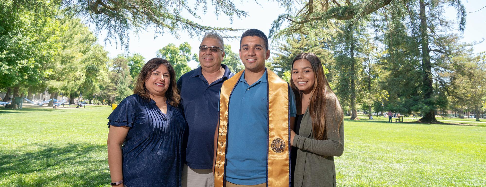 Parents pose with their ϲʿͼ graduate son on the quad 
